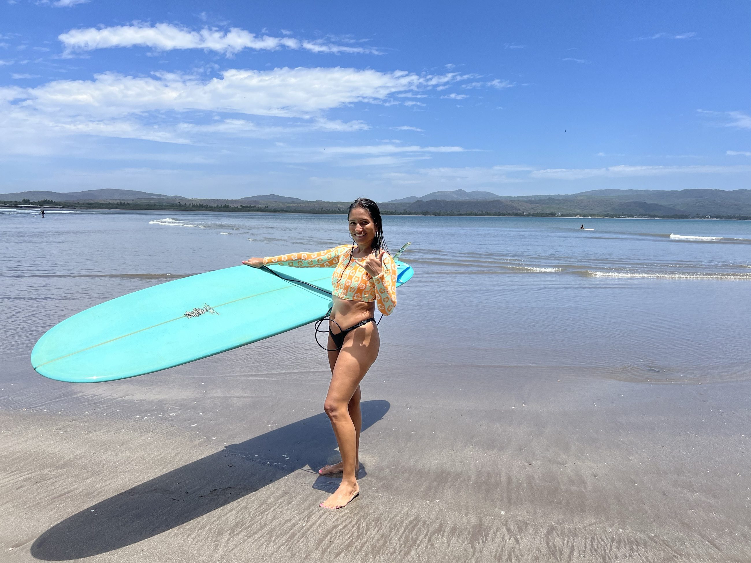 Alumna caminando por la orilla con una tabla bajo el brazo