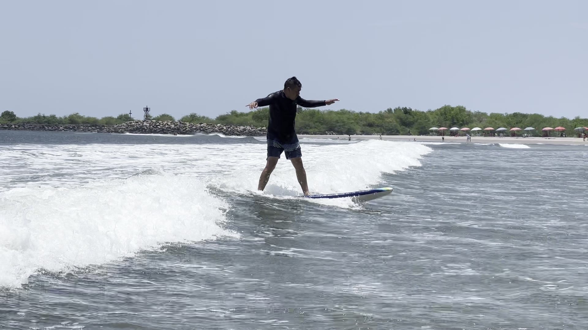 Persona surfeando con los brazos abiertos y equilibrada sobre una ola limpia